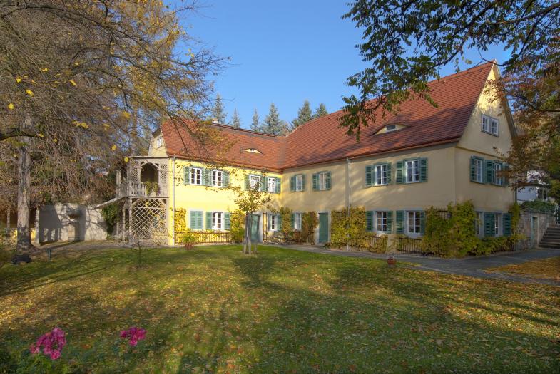 Das Carl-Maria-von-Weber-Museum mit idyllischem Garten in Hosterwitz. Das gelbe Haus mit Spitzdach hat zwei Etagen und grüne Fensterläden.